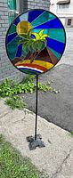 Full front view of circular stained glass panel on metal stake and weighted base