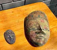 Both masks placed on a wooden surface showing size comparison and detailed patterns.