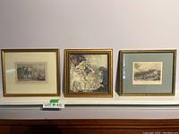 Set of three framed antique prints against a wall showing architectural and figure subjects.