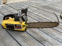 Photo of yellow Skil Saw gas chainsaw showing the full tool on wooden deck.