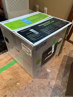 Sealed retail box of Epson WF-4740 printer showing product branding, feature highlights, and condition labels.