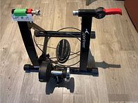 Front view of the Sportneer exercise bike converter stand showing the frame, resistance unit, and red clamp handle.