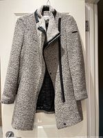 Front view of gray textured knit Calvin Klein ladies winter coat with black zipper and trim details, hanging on door.