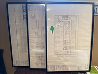 Three black IKEA RIBBA poster frames with architectural drawings inside, showing the frames from the front and side angles.