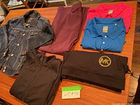 Full view of all clothing items laid out on table showing jean jacket, purple skirt, two Callaway golf shirts (red and blue), Michael Kors hoodie, and 90 Degree workout jacket