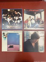 Four vintage vinyl records with visible album artwork including Chuck Mangione and Little River Band.