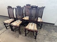 Set of six antique walnut dining chairs including five side chairs and one armchair, showing carved eagle motifs, cane backs, and upholstered seats.