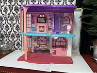 Front view of two-storey Barbie dollhouse showing overall structure with furniture placement and colorful interiors.