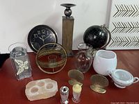 Wide shot of the decorative lot showing all items together on a wood surface including candle holders, globe, vase, bookends, salt holder, sugar dish, and wall clock.