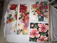 Four floral canvas prints laid out on a white surface showing varied colorful flower paintings
