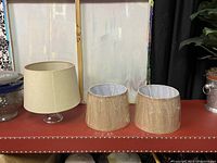 Three round lampshades arranged on table with one larger lampshade and two smaller wrapped matching lampshades