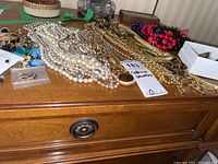 Overall assortment of jewelry laid out including necklaces, earrings, brooches, and pins