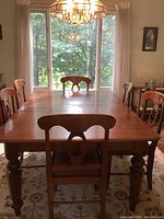 Full view of the assembled mahogany dining table with chairs around it and a large window in the background.
