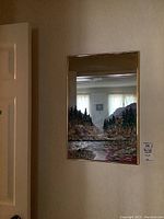 Full view of the framed mirror hung on a wall showing the overall look with the hand-painted landscape scene at the bottom.