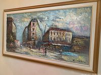 Front view of framed cityscape painting with buildings and pedestrians signed by C. Andrew