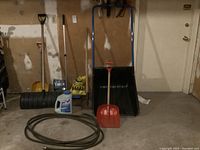 Photo showing entire lot including snow scoop, snow shovels, ice chopper, partial salt bag, deicer bottle, and coiled garden hose in garage.