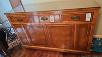 Front view of vintage wooden sideboard showing brass drawer pulls and door handles with glass top
