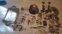 Overview of silverplate items including serving tray, cutlery, candlesticks, box, napkin rings, and small serving pieces