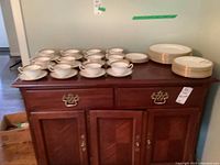 Overview of all plates, cups and saucers arranged on wooden sideboard