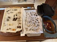 Top view of assorted earrings, purses, pins, and magnifier laid out on a table