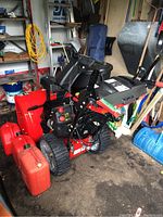 Side view of red Craftsman snow blower with three jerry cans placed alongside