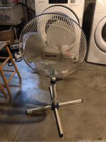 Front view of vintage Hatri-dy floor fan showing metal blades, protective grille, and tripod base.