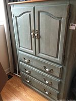 Full front view of the highboy showing two cabinet doors and three drawers with white ceramic and brass hardware.