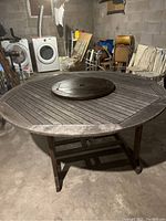 Octagonal wooden patio table with a central lazy Susan, showing weathered wood finish, in a basement setting.