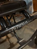 Close-up of Nexus branding on the black metal frame of the walker, showing wear and paint condition.