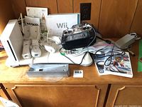 Full view of the Wii console, remotes, joysticks, charging dock, power adapter, sensor bar, game cases, and USB joystick.