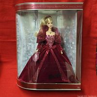 Front view of boxed Barbie doll showing burgundy velvet gown with glitter accents, in original packaging.