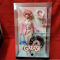 Front view of Barbie doll in original box showing doll dressed in pink jacket, white shirt, pink skirt, pearl necklace, and curly pink hair, with Grease logo and 30 years marking on front of box.