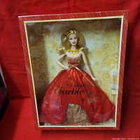 Front view of Barbie doll in original box showing red and gold dress and gold necklace.