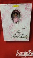 Front view of closed boxed Barbie as Eliza Doolittle collector doll with floral pink box and window showing doll's face.