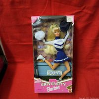 Front view of Barbie University Cheerleader Doll in original box with Duke uniform and accessories, showing full figure mid-jump and box branding.
