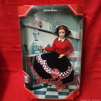 Front view of the boxed 1999 Coca-Cola Barbie doll showing the doll inside the clear window with red border packaging and Coca-Cola branding.
