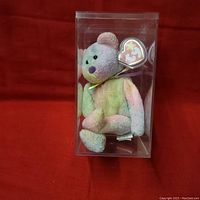 Front view of Groovy The Bear Ty Beanie Babies plush in clear plastic case showing rainbow colors and heart-shaped Ty tag