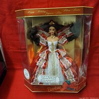 Barbie doll fully visible in original packaging, dressed in white and red detailed holiday gown.