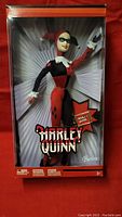 Front view of boxed Harley Quinn Barbie doll showing doll in classic jester costume and packaging with logo.