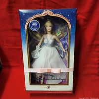 Full front view of Barbie Tooth Fairy doll in box with clear window, showing doll fully dressed in white fairylike dress with iridescent wings and satin pouch.