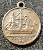 Close-up front view of the 1905 Victory metal medal featuring a detailed sailing ship and date.