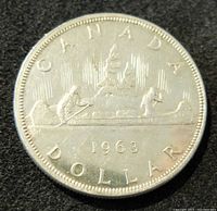 Reverse side of the 1963 Canadian silver dollar coin showing the canoe with two paddlers and the date 1963 along with the word CANADA and DOLLAR.