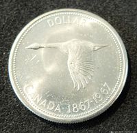 Obverse photo showing flying Canada goose and denomination 'DOLLAR CANADA 1867-1967'.