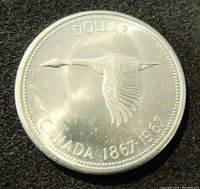 Obverse side of the 1967 Canada Silver Dollar coin showing a flying goose with the text 'DOLLAR CANADA 1867-1967'.