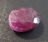 Close-up photo of the faceted 22.5-carat ruby, showing its oval shape, reddish-pink color, and visible internal and surface inclusions.