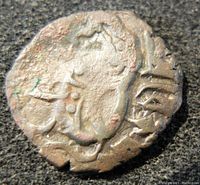 Obverse side of the coin featuring a human figure or deity with raised and stylized details.