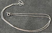 Sterling silver chain necklace displayed on a dark surface showing the chain detail and spring ring clasp.