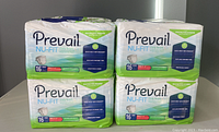 Four bags of Prevail Nu-Fit Daily Briefs stacked, clearly showing front packaging with brand name and product count.