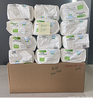 Stacked 18 bags of Secure Booster Pads Ultra, 20 count per bag, showing labels and packaging condition.