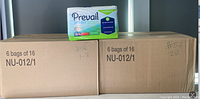 Two large cardboard boxes labeled NU-012/1 each containing 6 bags of 16 Prevail Nu-Fit Daily Briefs Medium 32" x 44". One sealed bag of the briefs placed on top of the boxes for display.